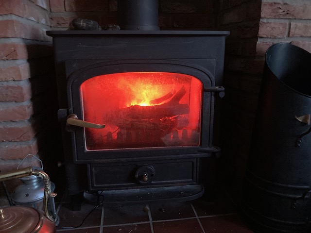 Envflame cartridge placed inside a traditional log-burning stove, glowing like a real fire